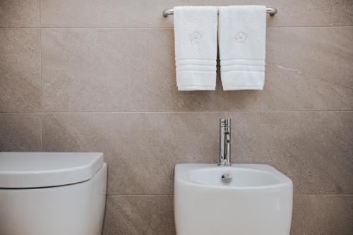 a bathroom with a toilet and towels on the wall at PALAZZO FRANGIPANE in Salve
