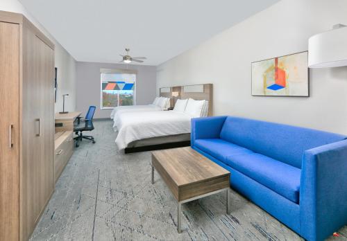 a hotel room with a bed and a blue couch at Holiday Inn Express & Suites North Dallas at Preston, an IHG Hotel in Dallas