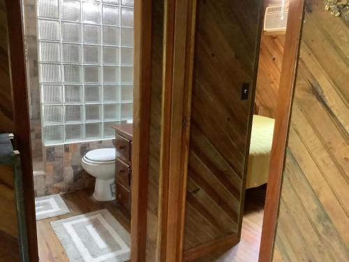 a bathroom with a toilet and a wooden door at Tropical Treehouse in Sandy Bay