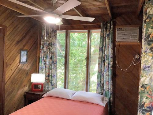 um quarto com uma cama, uma ventoinha de tecto e uma janela em Tropical Treehouse em Sandy Bay