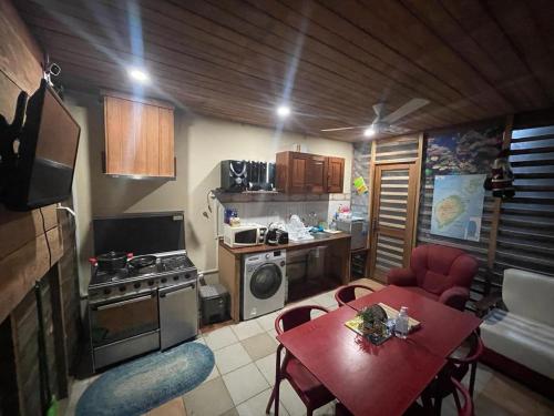 uma pequena cozinha com uma mesa vermelha e cadeiras num quarto em RALUX house em São Tomé