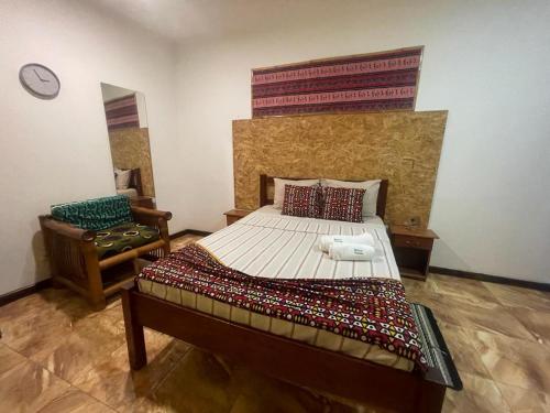 um quarto com uma cama grande e uma cadeira em RALUX house em São Tomé