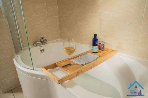 a glass of wine sitting on a bath tub at Spacious and Homely 3 Bedroom Flat - SuiteLivin in Gateshead