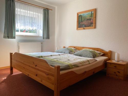 1 dormitorio con cama de madera y ventana en Ferienwohnung Grieser en Geising