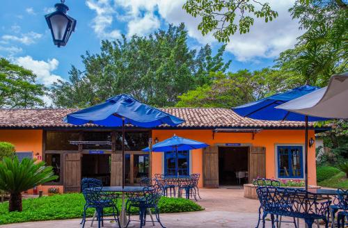 a patio with tables and chairs with blue umbrellas at Itu Garden - SPA e Resort Saudavel in Itu