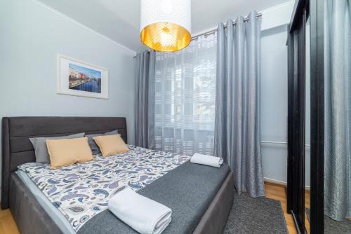 a bedroom with a bed and a large window at Apartament Gersona 4 in Bydgoszcz