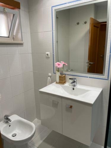 a white bathroom with a sink and a mirror at AP Roberand in Albufeira