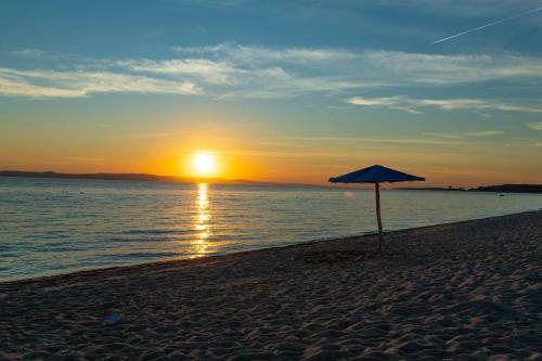 an umbrella on a beach with the sun setting at Oniro Luxury Villas in Toroni