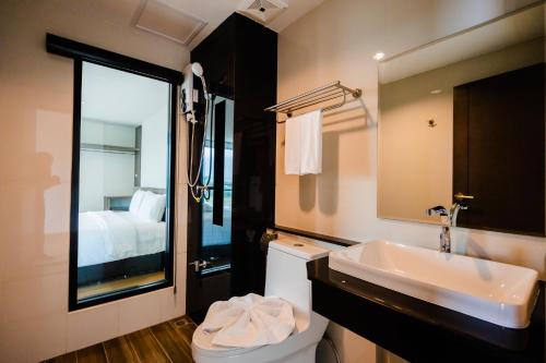uma casa de banho com um lavatório, um WC e um espelho. em JS HOTEL em Hat Yai