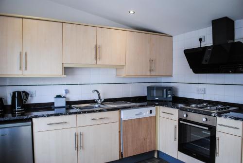 a kitchen with wooden cabinets and a stove top oven at Sky Lounge - Beachfront top floor apartment with stunning veiws in Kent