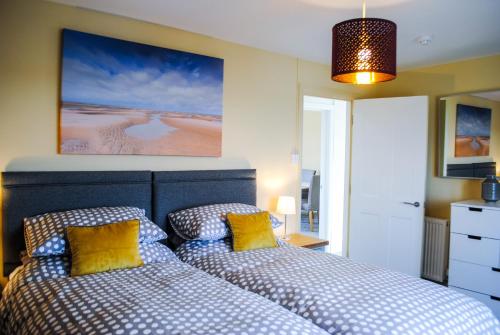 1 Schlafzimmer mit 2 Betten und gelben Kissen in der Unterkunft Sky Lounge - Beachfront top floor apartment with stunning veiws in Kent