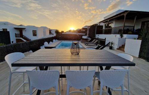 a wooden table and chairs on a patio with the sunset at Villa Little Star in Playa Blanca
