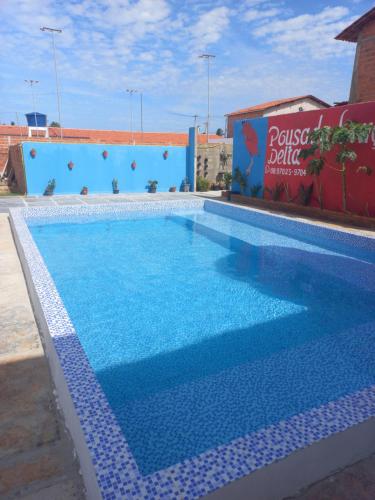 a swimming pool with blue water in front of a building at Pousada Lençóis do Delta in Tutóia