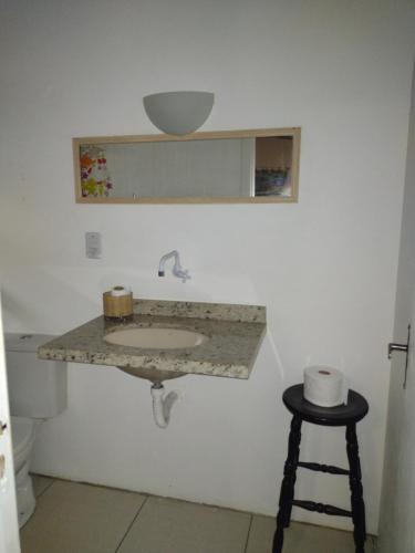 a bathroom with a sink and a stool at Apartamento - Praia da Ferrugem com Espaço Gourmet in Palhocinha