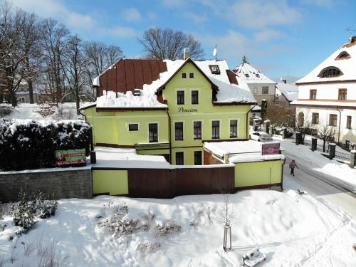 a yellow house with a brown roof in the snow at Penzion Pokorny in Jablonec nad Nisou