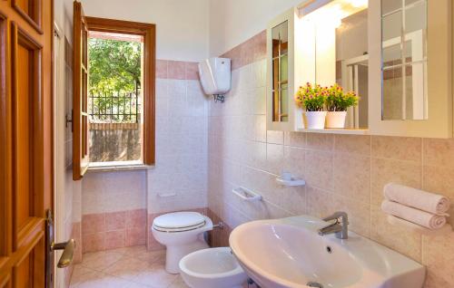 Un baño con lavabo, inodoro y ventana. en Villa Belvedere, en Capo Vaticano