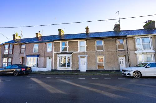 波斯馬多格的住宿－Newly-renovated, mid-terrace cottage in Porthmadog，一座大型砖屋,前面停有两辆车