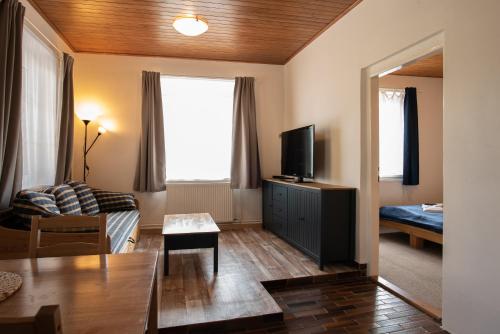 una pequeña sala de estar con sofá y TV en Pension Styl en Bedřichov