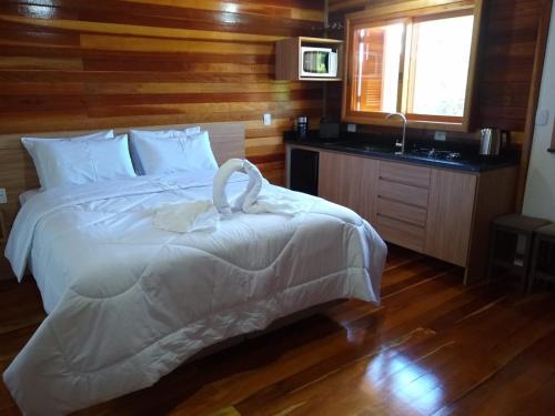 1 dormitorio con cama blanca, lavabo y ventana en Sítio Passo do Carro, en São Francisco de Paula