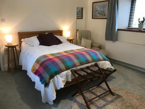 a bedroom with a bed with a colorful blanket on it at Wrens Nest in Axminster