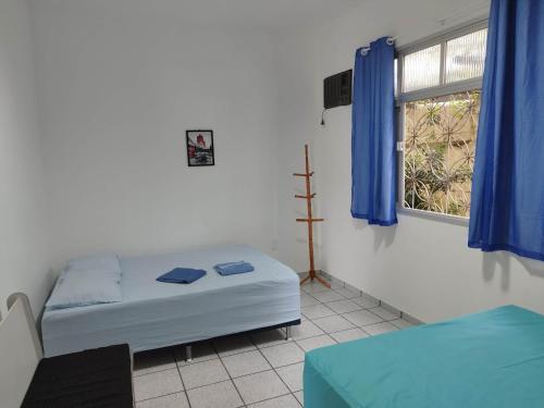 une chambre avec un lit et une fenêtre avec des rideaux bleus dans l'établissement Seu Apto na Praia da Costa 13 Barato Completo TV Geladeira Fogão Ar Cond Local Excelente Centro, à Vila Velha