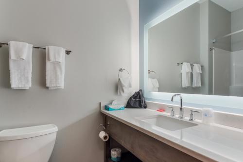 a bathroom with a sink and a toilet and a mirror at SureStay Plus Hotel by Best Western Highland Poughkeepsie in Highland