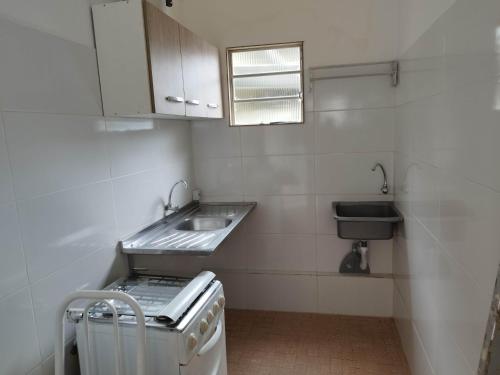 une petite cuisine blanche avec un évier et un lavabo dans l'établissement Seu Apto na Praia da Costa 13 Barato Completo TV Geladeira Fogão Ar Cond Local Excelente Centro, à Vila Velha