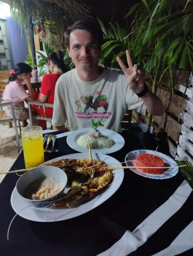 a man sitting at a table with plates of food at Rashuthere Maldives in Rasdu