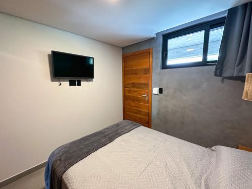 a bedroom with a bed and a flat screen tv at Casa Oceano Praia do Rosa, apartamentos pé na areia, Praia do Rosa in Praia do Rosa
