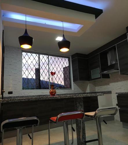 un bar con tres taburetes en una cocina con ventana en Xiomara, en Quito