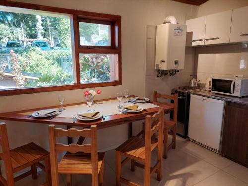 a kitchen with a wooden table with chairs and a counter at Destinar Apartments in San Carlos de Bariloche