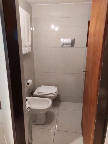 a bathroom with a toilet and a toilet paper dispenser at Destinar Apartments in San Carlos de Bariloche