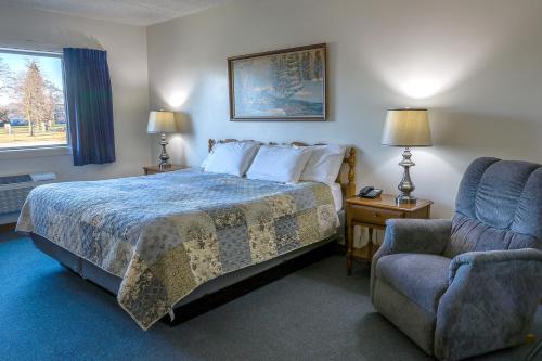 a hotel room with a bed and a chair at Lighthouse Inn - Two Rivers in Two Rivers
