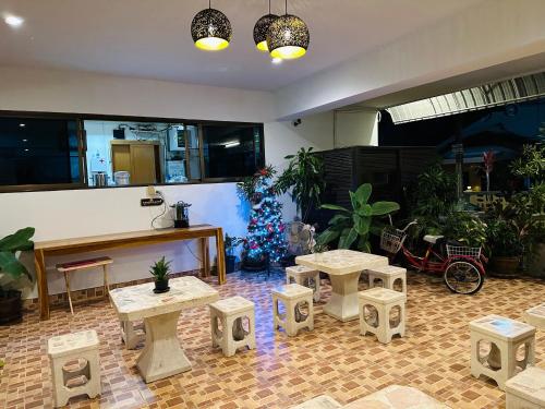 a room with a christmas tree and tables and stools at JJ Palace เจเจ พาเลซ in Ban Si Than