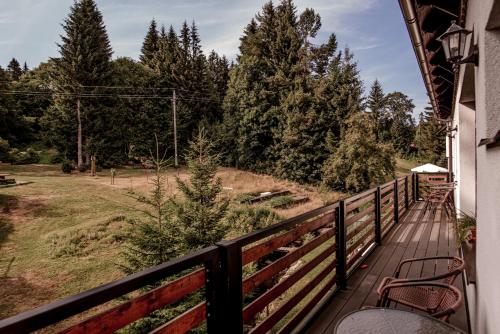 a balcony with chairs and a fence and trees at Pension Styl in Bedřichov