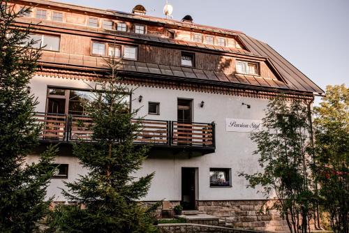 a building with a balcony on the side of it at Pension Styl in Bedřichov