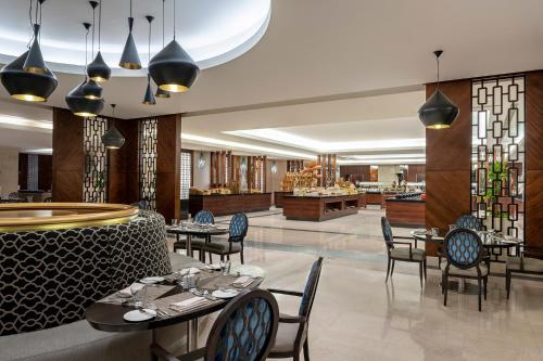 a restaurant with tables and chairs and a bar at Swissotel Al Maqam Makkah in Makkah