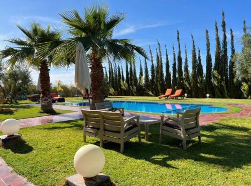 a table and chairs next to a swimming pool with palm trees at Spacious Moroccan Private Villa With Heated Pool in Marrakesh