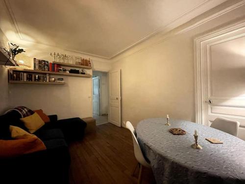 uma sala de estar com uma mesa e um sofá em Appartement familial douillet chez Anja & Charles em Paris