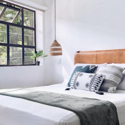 a bedroom with a bed with pillows and a window at 574 Hotel in Medellín