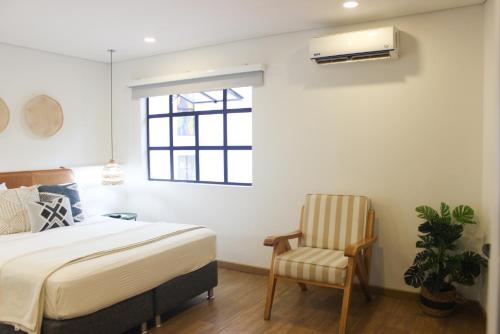 a bedroom with a bed and a chair and a window at 574 Hotel in Medellín