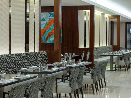 a dining room with tables and chairs and a painting at Swissotel Makkah in Makkah