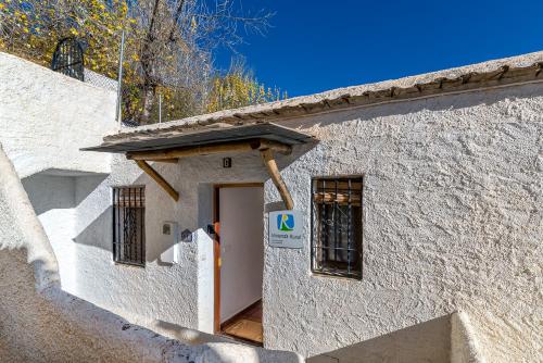 a white building with a door with a sign on it at Apartamento Casa Manuela en Capileira - Alpujarra in Capileira