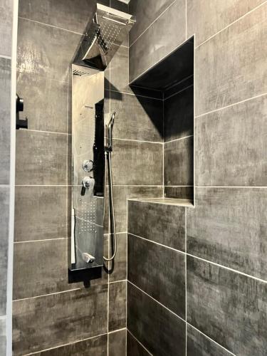 y baño con ducha y pared de azulejos. en Chambre studio tout confort en Boussu
