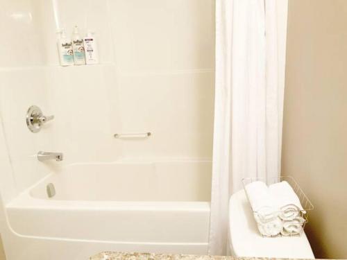 ein weißes Bad mit einer Badewanne und einem Duschvorhang in der Unterkunft NairaVilla: upscale accommodation for groups in Regina