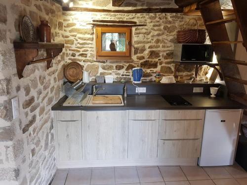eine Küche mit einer Theke und einem Waschbecken in einer Steinwand in der Unterkunft Le Four de La Jugie in Le Lonzac