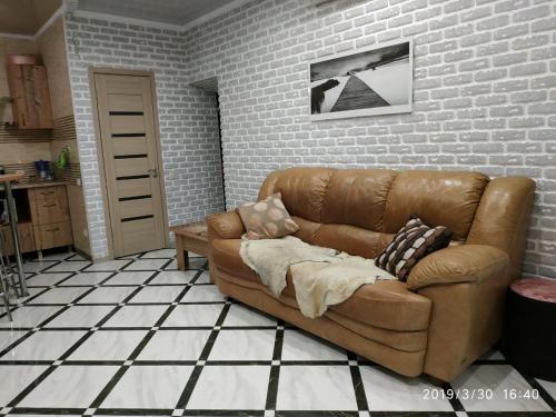 a brown couch in a living room with a brick wall at Apartments on Kashyns'koho Street 6 in Myrhorod