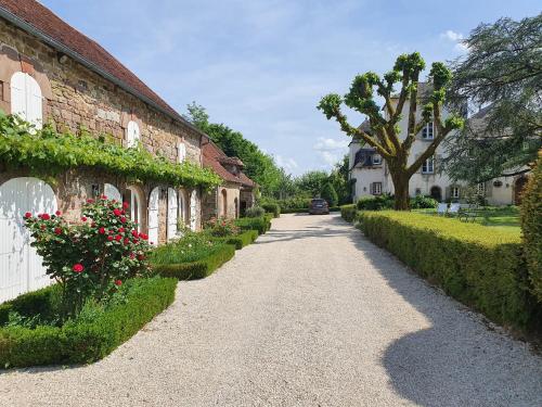une route en gravier à côté d'un bâtiment en briques orné de fleurs dans l'établissement Superbe gîte avec vue sur les vignes, dans le parc d'un manoir du 18ème siècle, à Saint-Bazile-de-Meyssac
