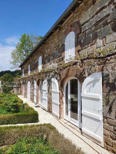 a brick building with white doors and windows at Superbe gîte avec vue sur les vignes, dans le parc d'un manoir du 18ème siècle in Saint-Bazile-de-Meyssac