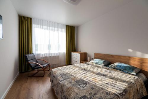 a bedroom with a bed and a chair and a window at NEW Apartment on Zhasmynova Street 5b in Lviv